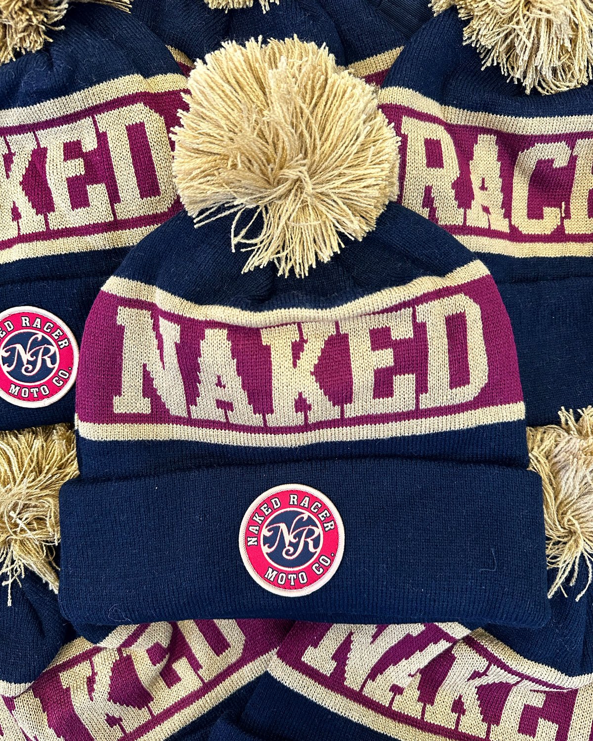 Naked Racer Pom Pom embroidered caps by Melbourne Merch - crisp embroidery, good lighting, frame-filling composition