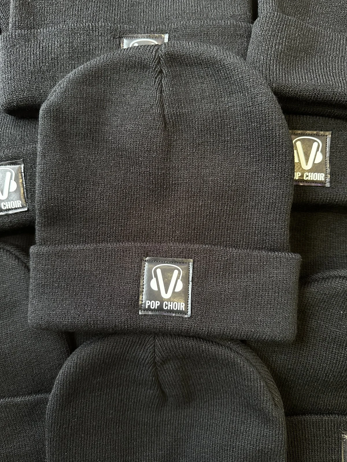 Pop Choir embroidered caps in repetition showing custom labels